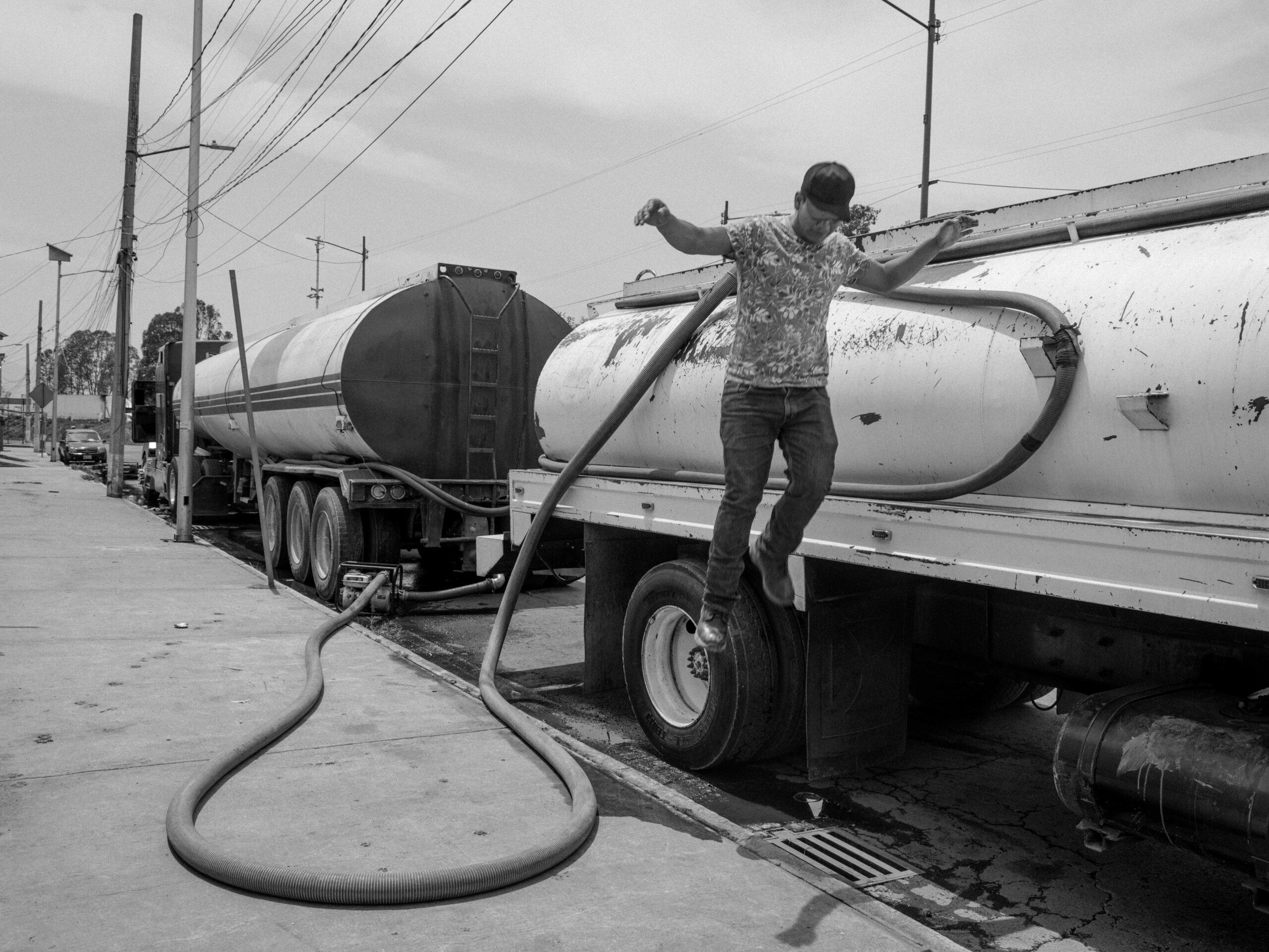 A “pipero” — a tanker truck driver who distributes drinking water to neighborhoods where it is in short supply — jumps from a tanker truck, May 27, 2024.