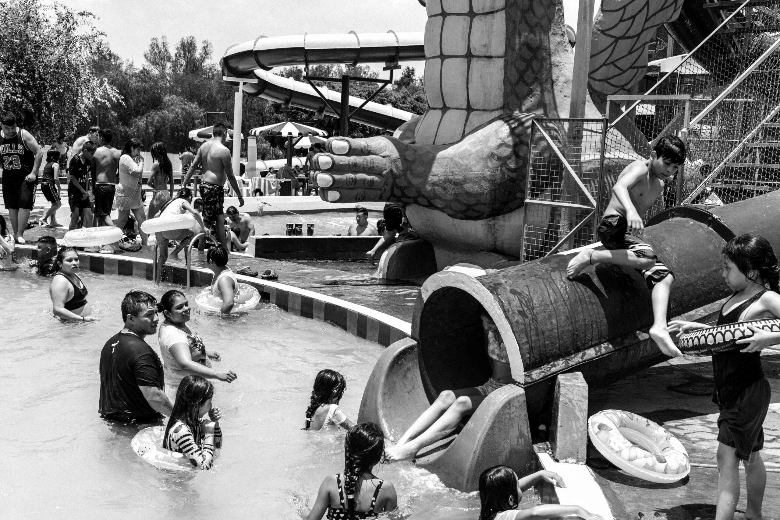 Children jump into the water on a slide while a couple looks on at Balneario Elba, May 26, 2024.